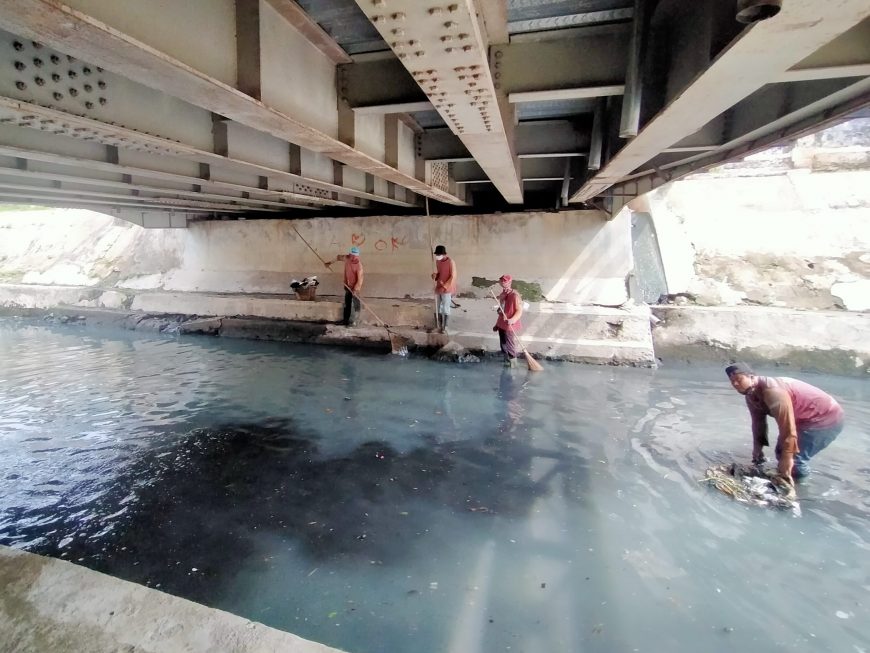 Petugas dari Dinas PU Bina Marga dan Pematusan Surabaya tampak membersihkan sungai di depan 'Mat Sapri' tidur /foto: Bicara Surabaya