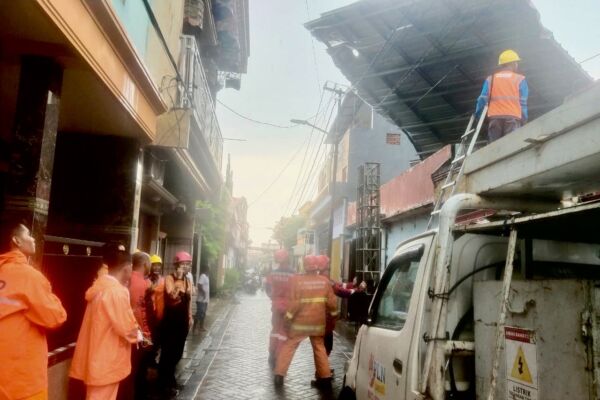 Petugas dari BPBD Kota Surabaya melakukan perbaikan atap rumah warga pasca hujan deras dan angin kencang, Minggu (5/1/2025) sore.