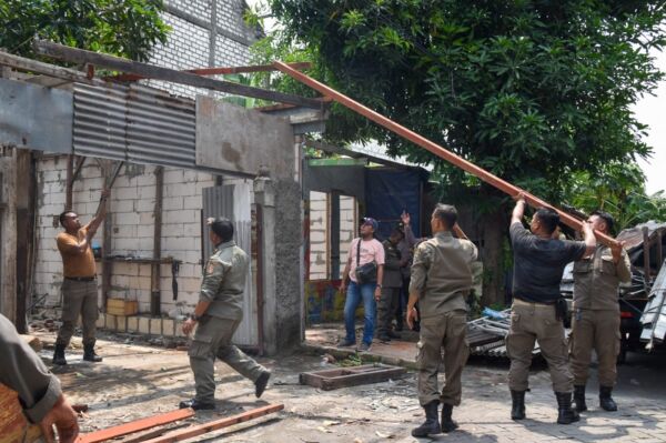 Personel Satpol PP melakukan penertiban bangunan liar di Tambak Wedi Baru Surabaya, Minggu (5/1/2025).