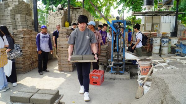 Teo Ryan, mahasiswa dari Singapura sedang membawa paving yang sudah dicetak (Foto: Humas PCU)