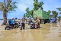 Petugas mengatur lalu lintas di jalur Sampang-Bangkalan yang terendam banjir akibat sungai meluap (Foto: Dok Polres Sampang-Ist/BS)