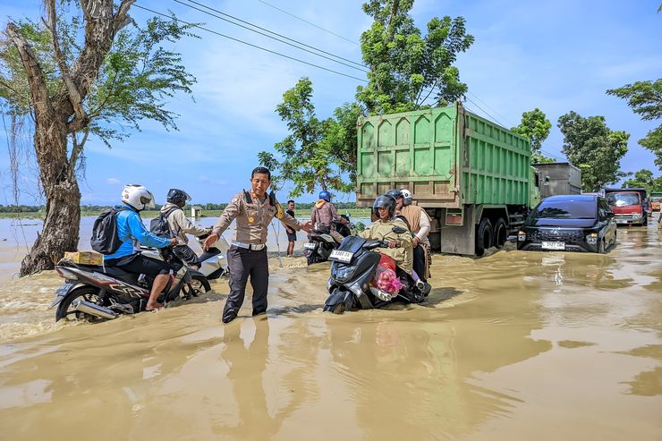 Petugas mengatur lalu lintas di jalur Sampang-Bangkalan yang terendam banjir akibat sungai meluap (Foto: Dok Polres Sampang-Ist/BS)