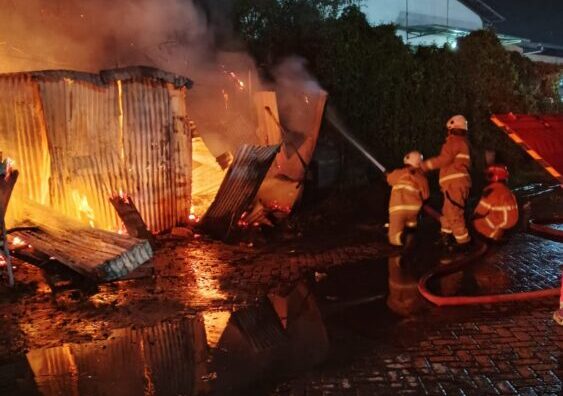 Petugas DPKP Surabaya berusaha menjinakkan apii yang membakar warung semi permanen. (Foto: Command Cenetr 112-Ist/BS)