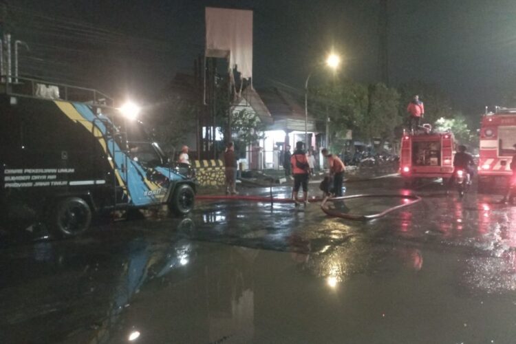Petugas DPKP Pasuruan membersihkan lumpur usai banjir agar bisa dilalui. Banjir yang akibatkan jalur utama pantura tertutup. (Foto: Istimewa)