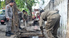 Mengembalikan fungsi dan perawatan drainase, petugas Satpol PP Surabaya menertibkan lapak padagang di Manukan yang berada diatas drainase. (Foto: Satpol PP Surabaya/Ist)