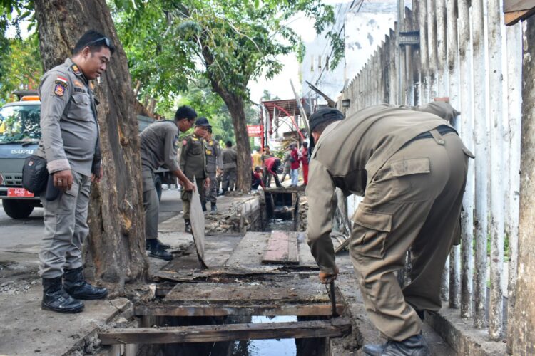 Mengembalikan fungsi dan perawatan drainase, petugas Satpol PP Surabaya menertibkan lapak padagang di Manukan yang berada diatas drainase. (Foto: Satpol PP Surabaya/Ist)
