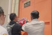 Petugas gabungan menempelkan stiker pelanggaran pada rumah kos yang tidak berizin. (Foto: dok Satpol PP Surabaya)